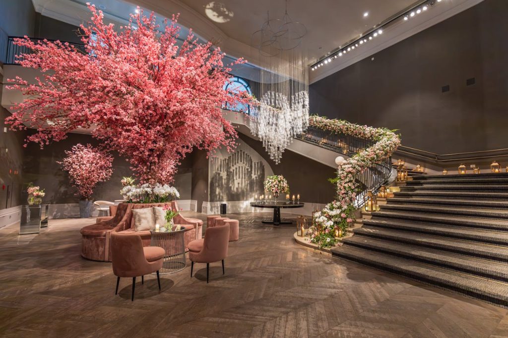 Luxurious hotel lobby with grand floral arrangements and elegant staircase.